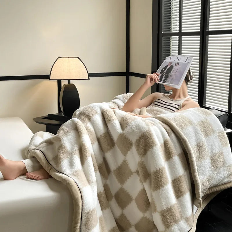 A woman reading on a sofa under the khaki checked fleece blanket