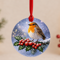Round glass tree decoration with a robin on red-berried holly in the snow, hanging on a red ribbon