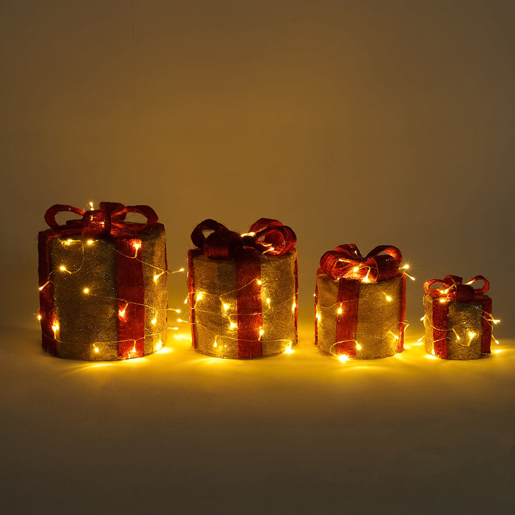 Four lit gold sisal gift box decorations with red bows in a row, from large to small