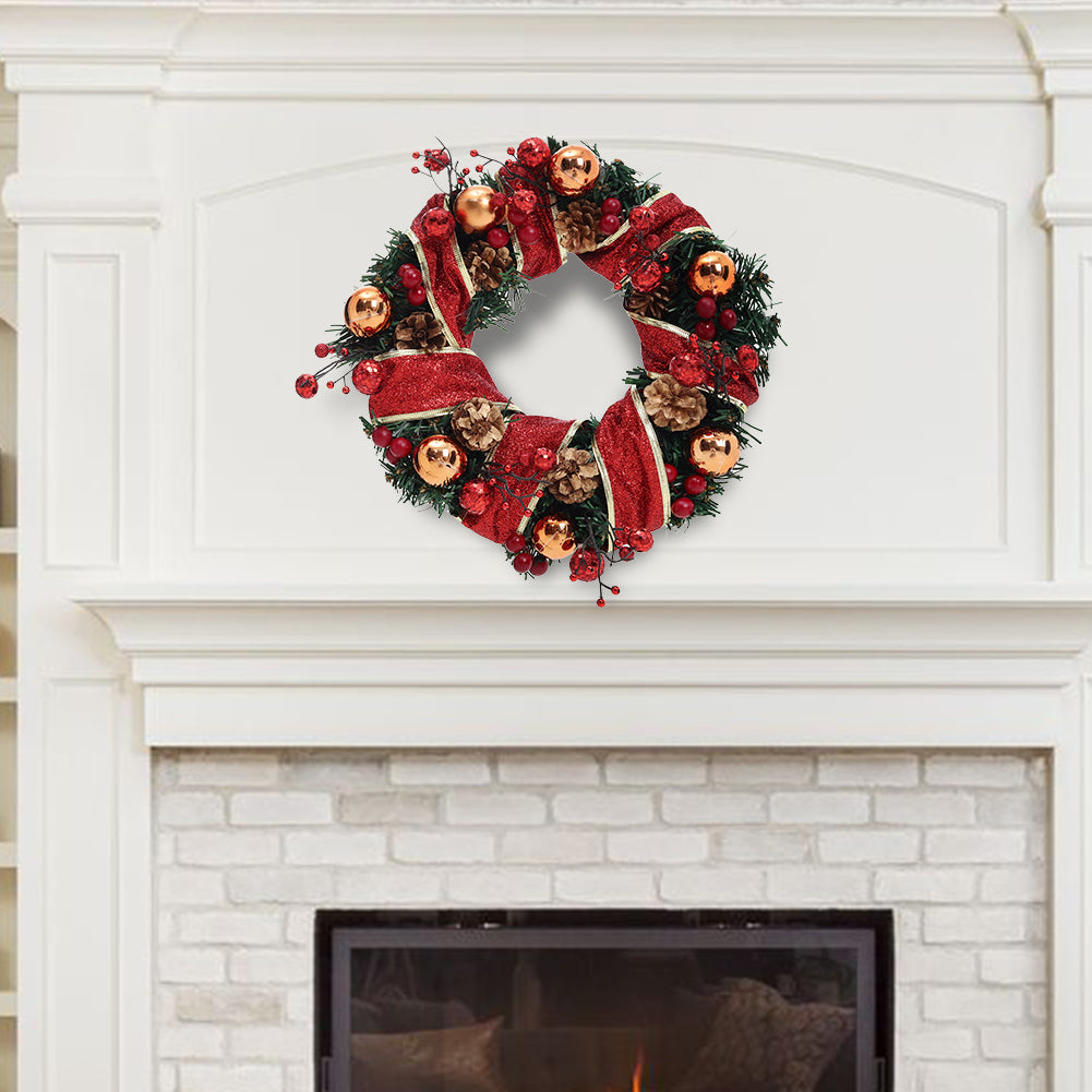 Red ribbon Christmas wreath with gold baubles and pine cones hung above a white fireplace