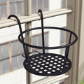 Empty black iron pot holder with two hooks hung over a balcony rail, latticed base showing