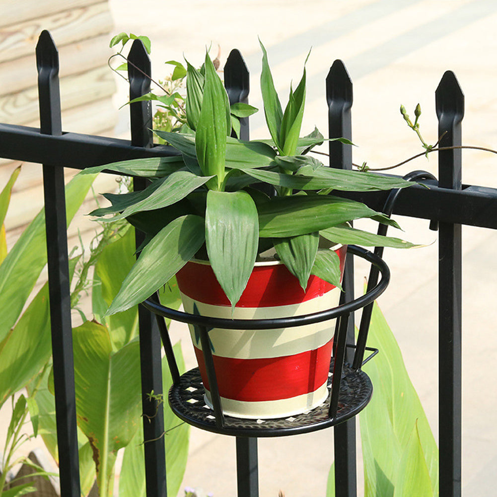 Black pot holder hooked on a spear-top fence holding a striped pot of spider plant
