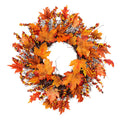 Artificial wreath of orange and red maple leaves and glossy berries on a twig base, on white