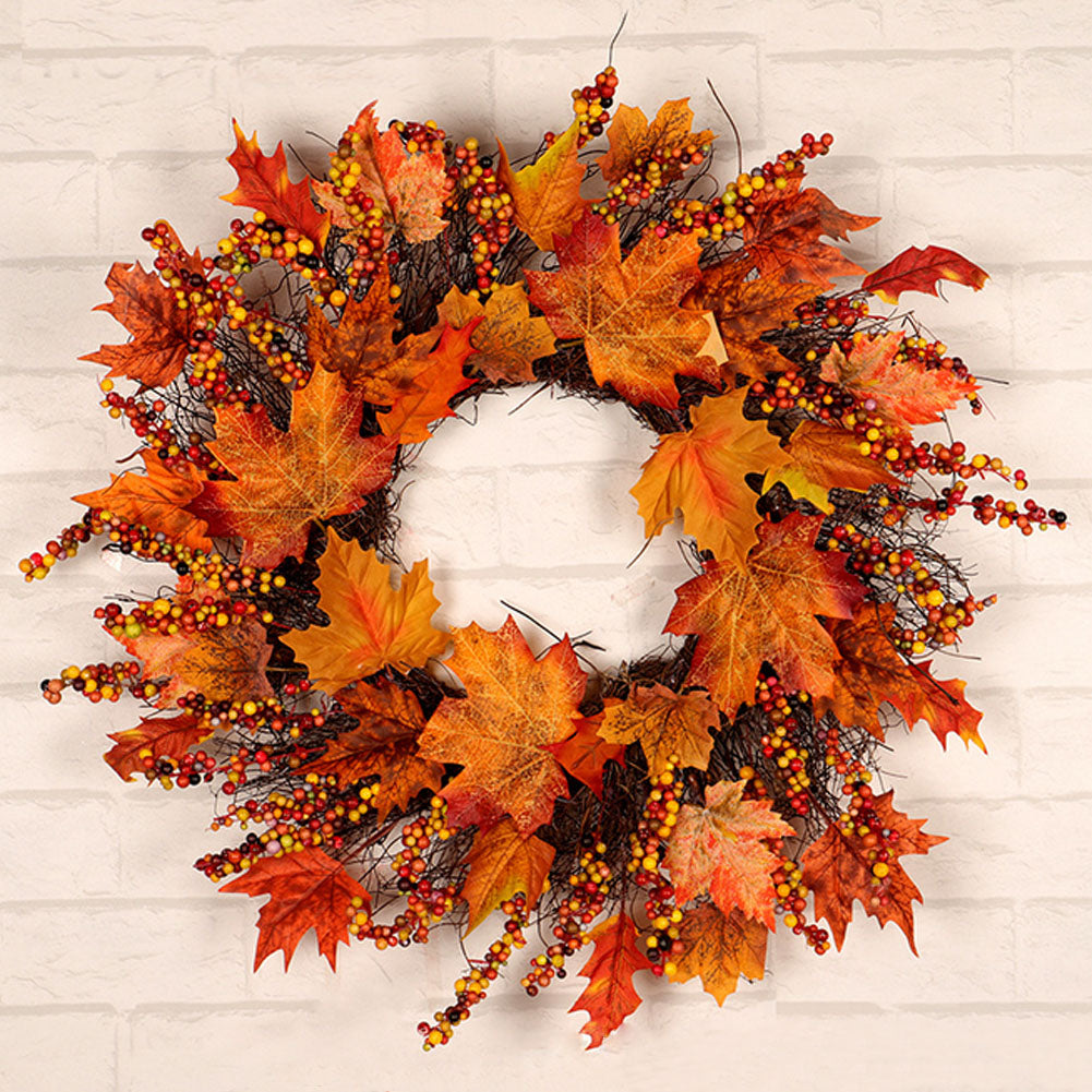 Close view of the maple leaf and orange berry wreath on a white brick wall