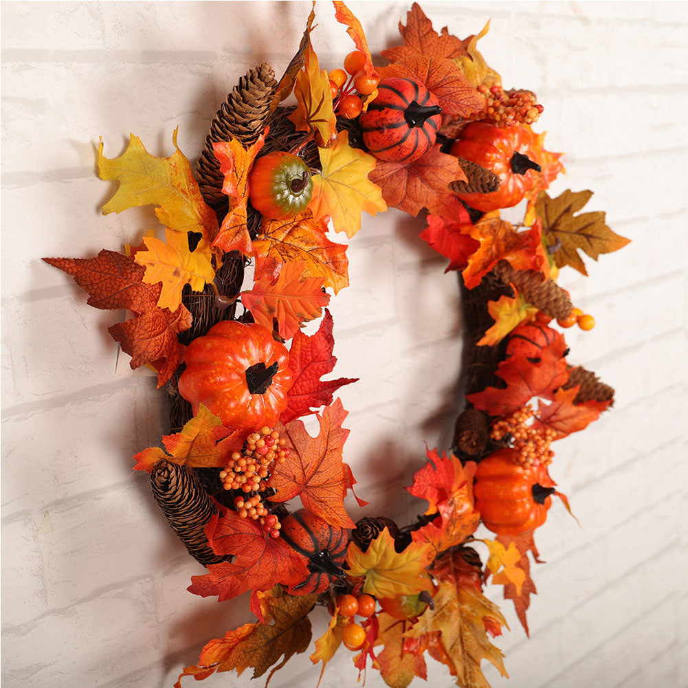 The autumn wreath of maple leaves and pumpkins on a white wall, seen from the side