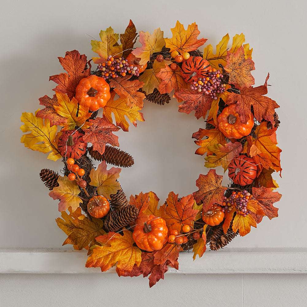 The full autumn wreath with its lights glowing on a white wall