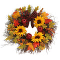 Artificial wreath of sunflowers, maple leaves, berries and red fruits with a red and black plaid bow, on white