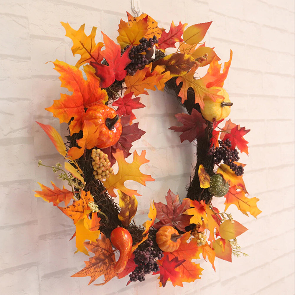 The autumn wreath of maple leaves and pumpkins on a white brick wall