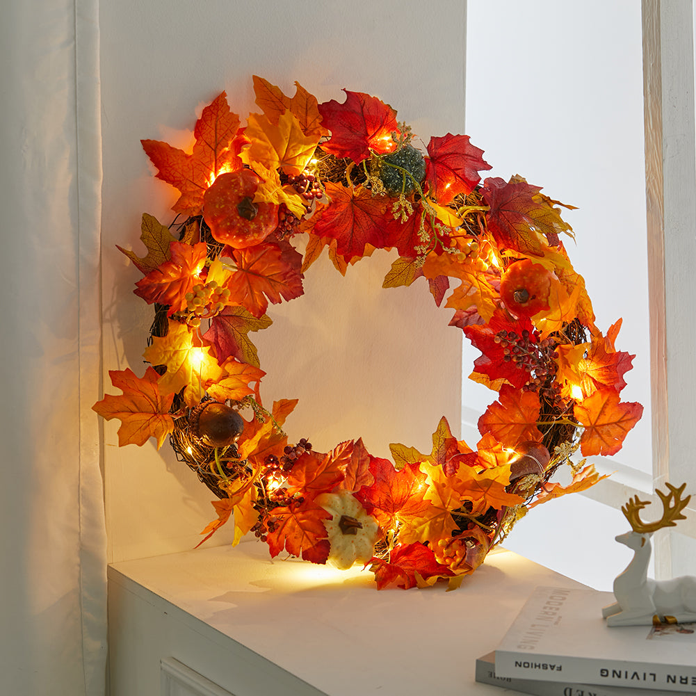 The branch ring autumn wreath with its lights glowing on a white wall above a shelf