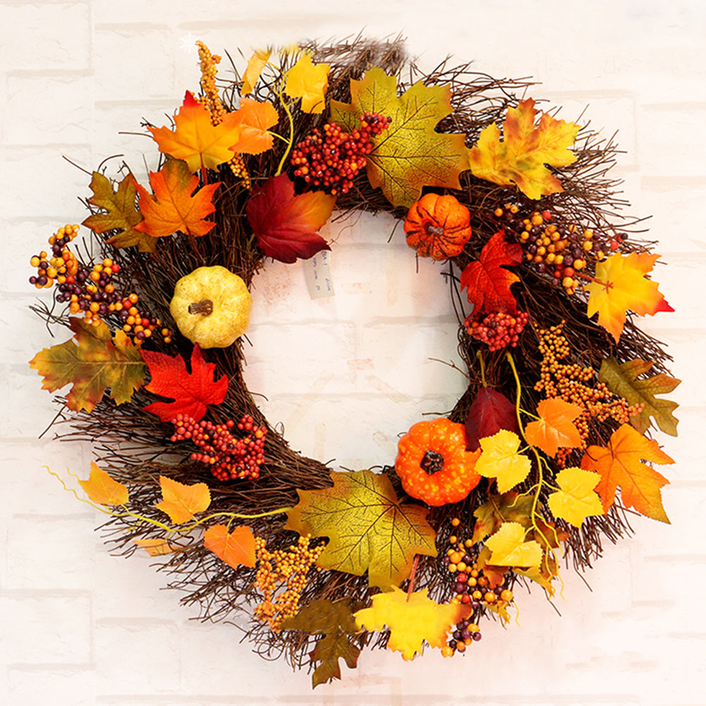 Autumn maple leaf and pumpkin wreath on a woven twig ring against a white brick wall