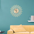 Round gold wall clock with drop-shaped metal rays and crystal beads on a teal living room wall