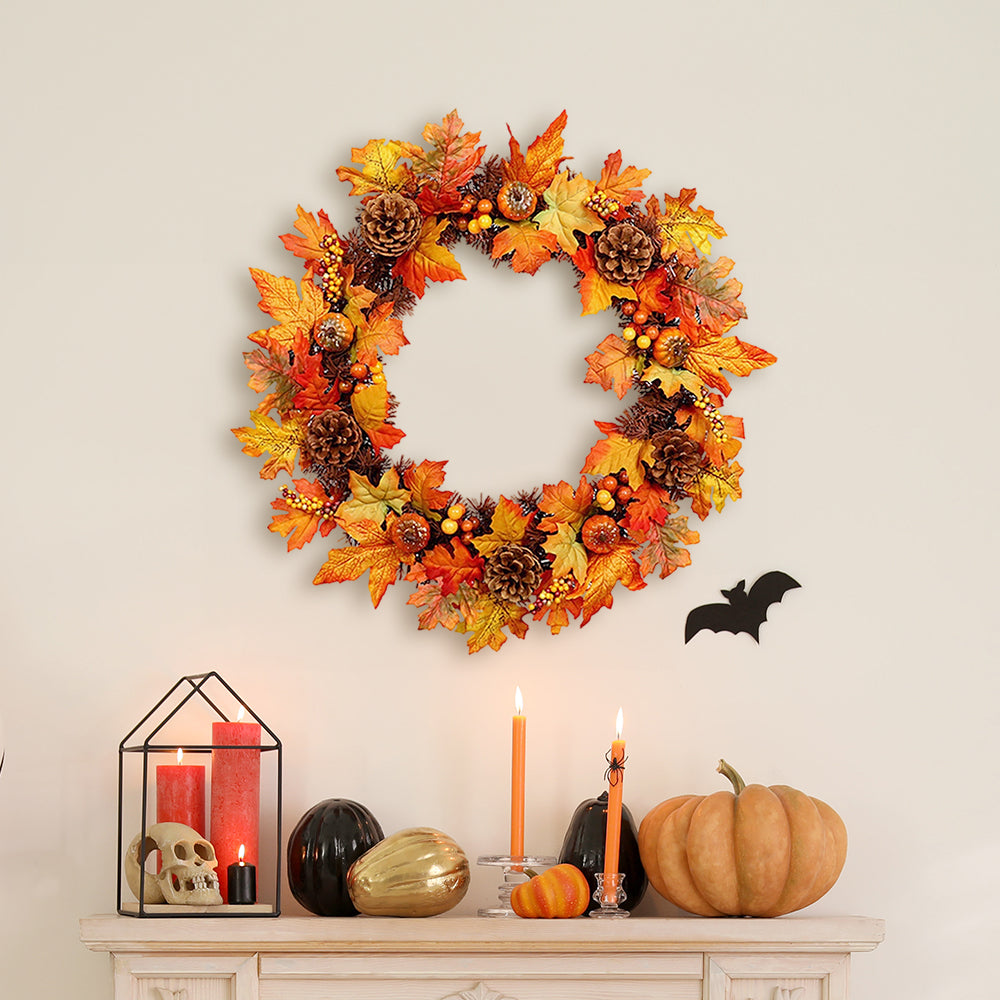 The orange autumn wreath hanging above a white fireplace shelf with candles and small pumpkins