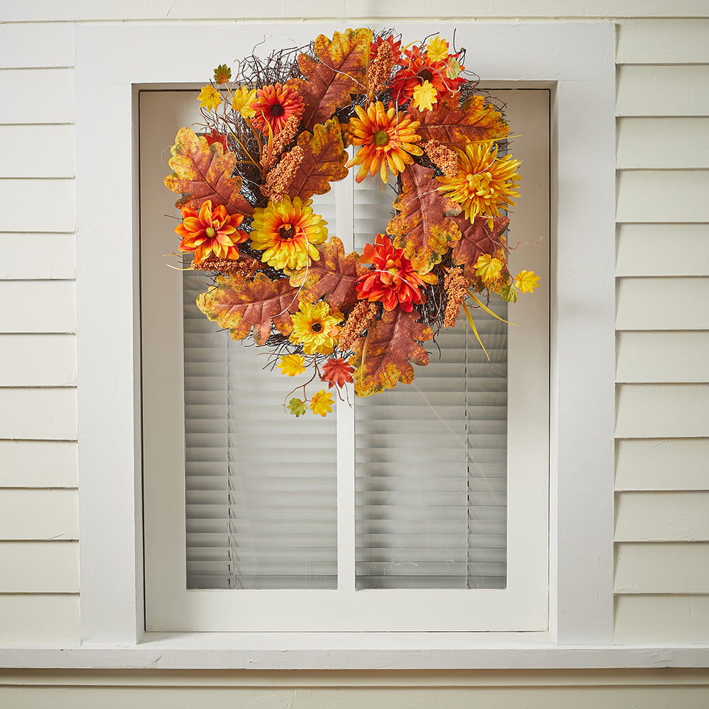 The daisy and maple leaf wreath hanging on a white window