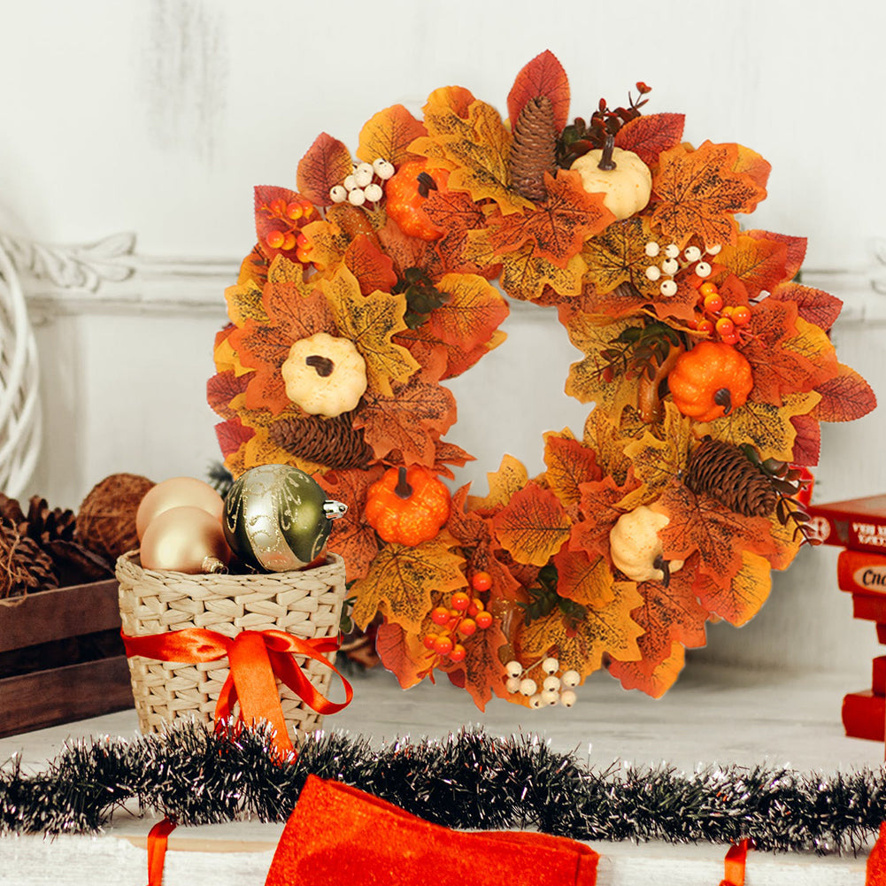 The white and orange pumpkin wreath on a wall above wrapped gifts and red tinsel