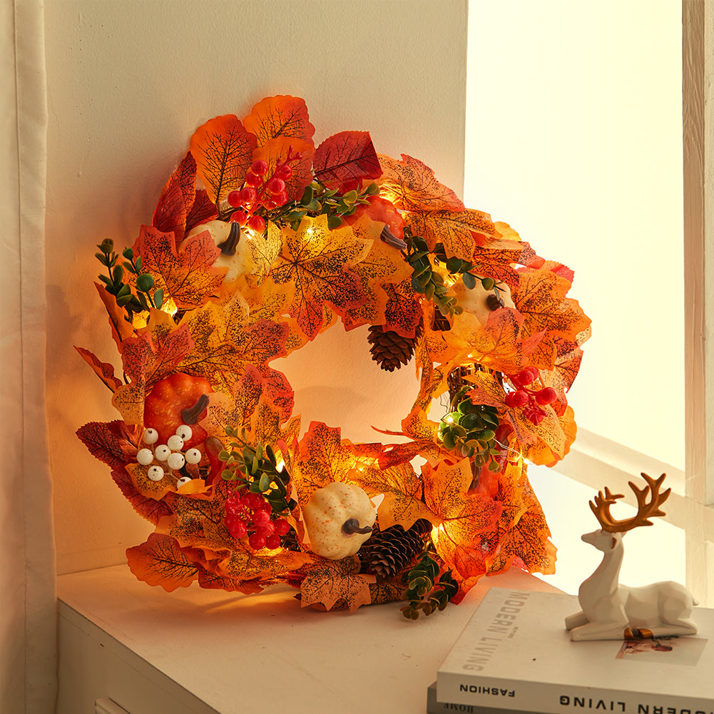 The pumpkin wreath glowing with its lights on in warm light
