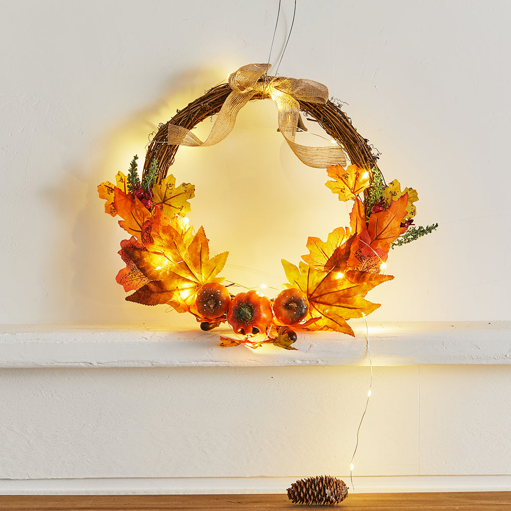 The harvest wreath with its lights glowing on a pale wall