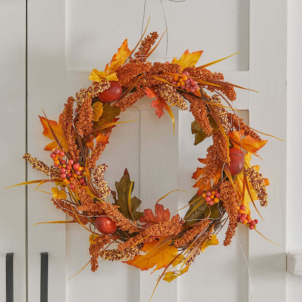 Orange autumn sorghum wreath on a white cupboard door with black handles
