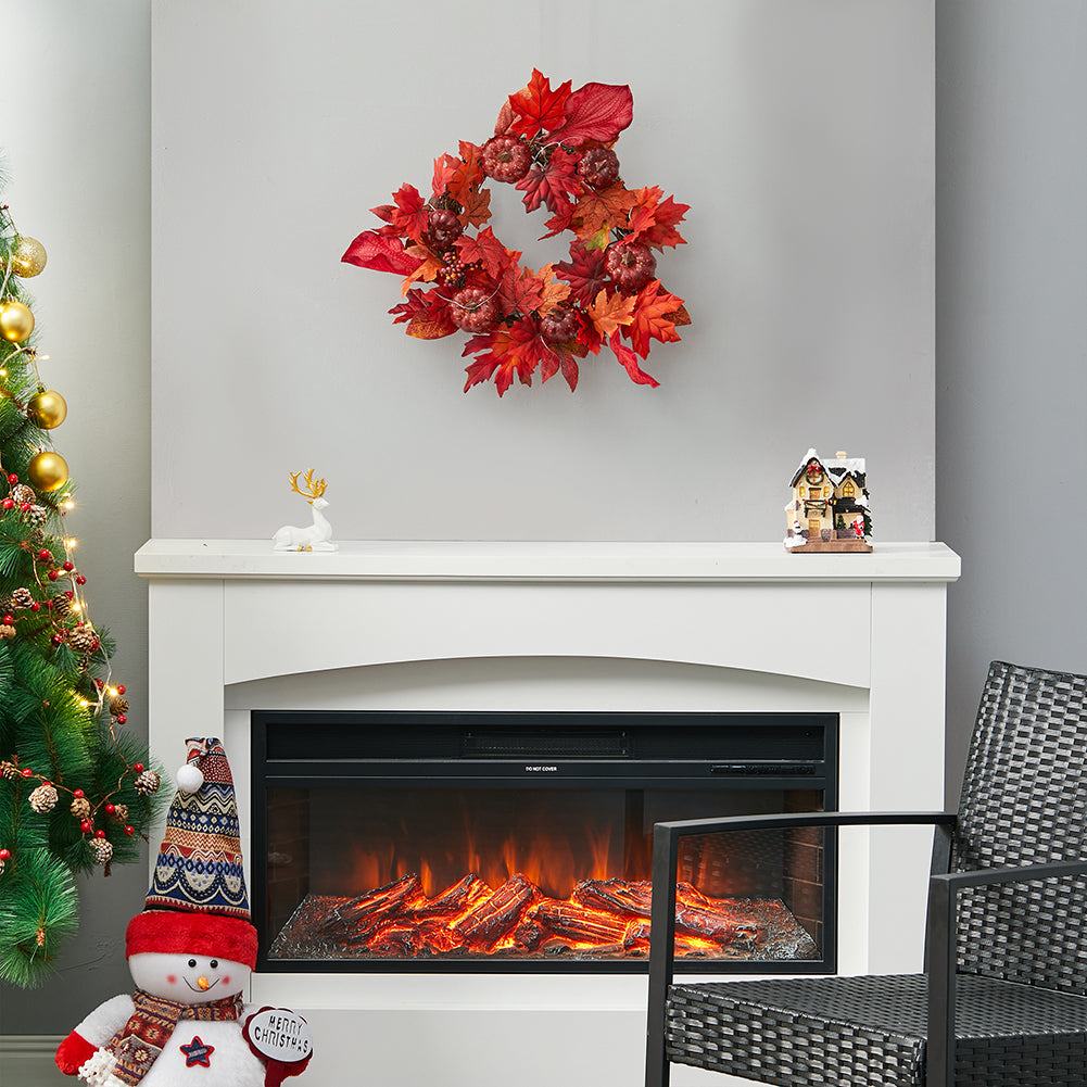 Red maple leaf wreath on a wall above an electric fireplace, with a small Christmas tree beside it