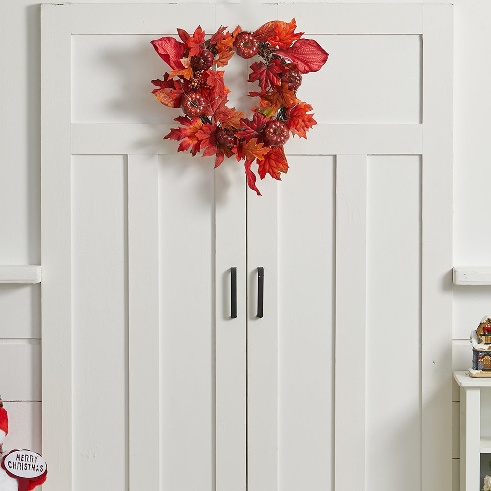 Red autumn maple leaf wreath hanging on a white panelled door