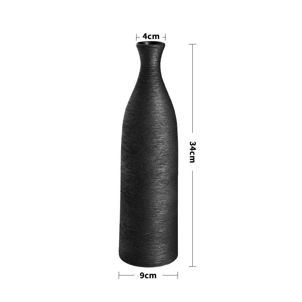 The black bottle vase on white with lines marking its 34 cm height and 9 cm width
