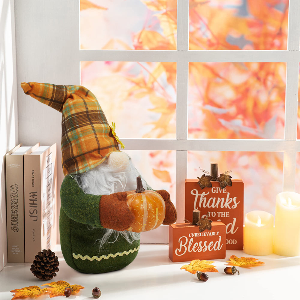 Autumn gnome holding a pumpkin on a white windowsill with books, candles and autumn leaves