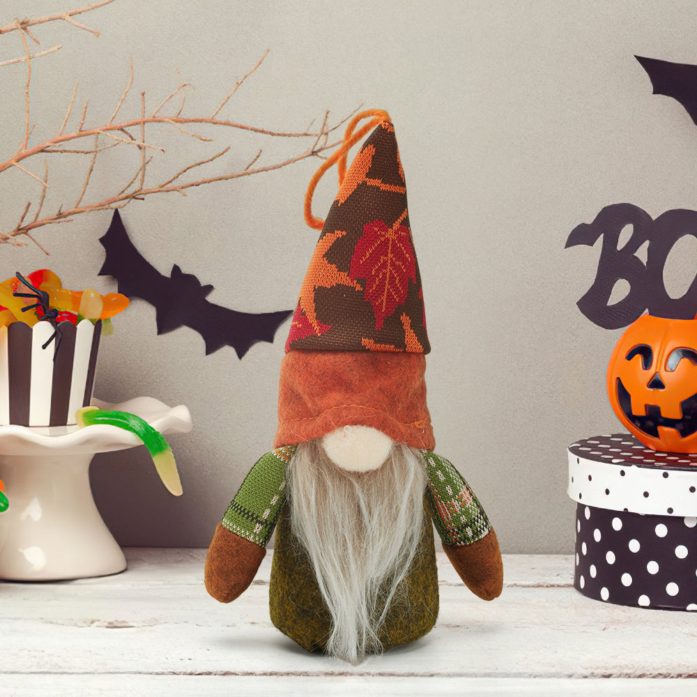 Fabric gnome with a tall orange and brown maple-leaf hat, pale beard and green plaid arms on a white shelf