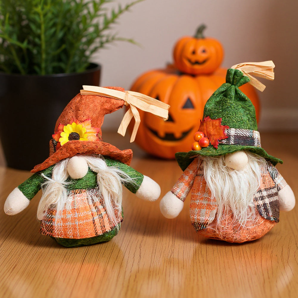 The two autumn gnomes with their arms out on a wooden floor beside carved pumpkins
