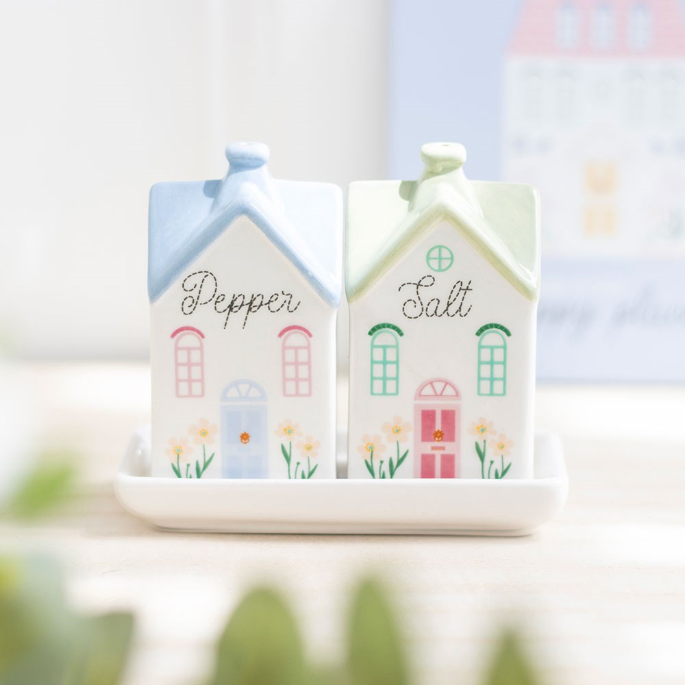 Two ceramic townhouse shakers marked Pepper and Salt on a white tray on a table