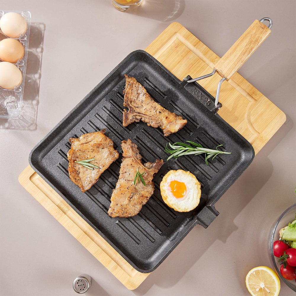 Top view of the grill pan with grilled pork and an egg, its wooden handle folded out