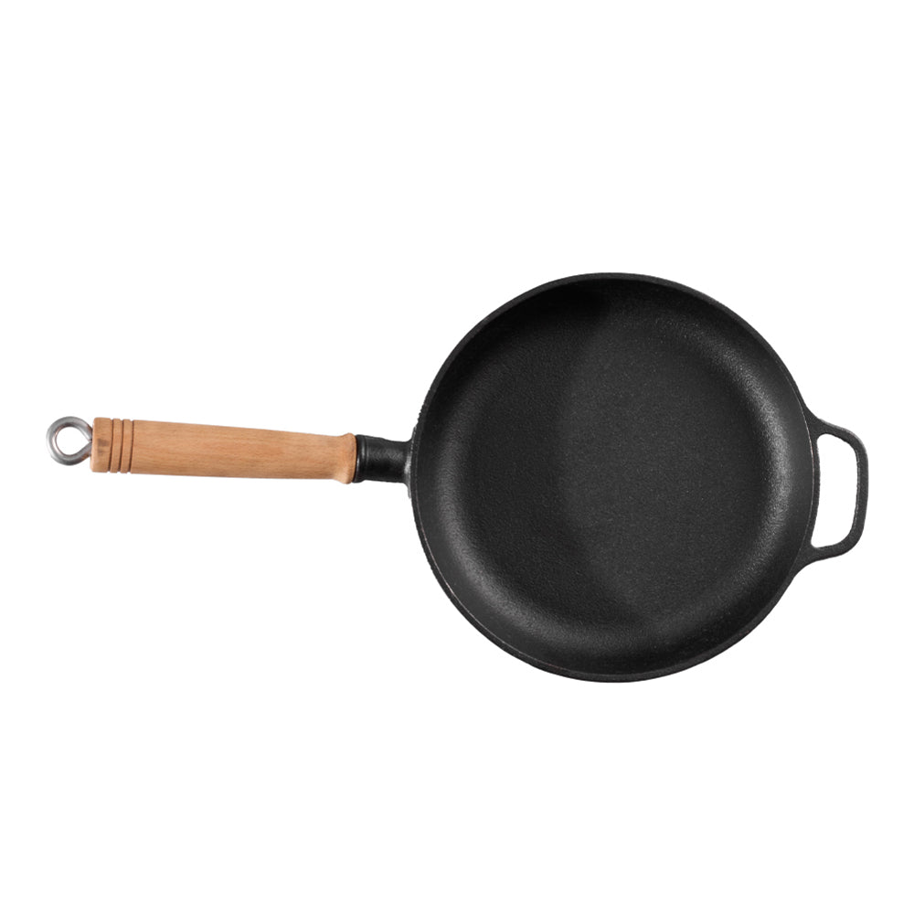 Round black cast iron skillet with a long wooden handle and a small loop handle, seen from above on white