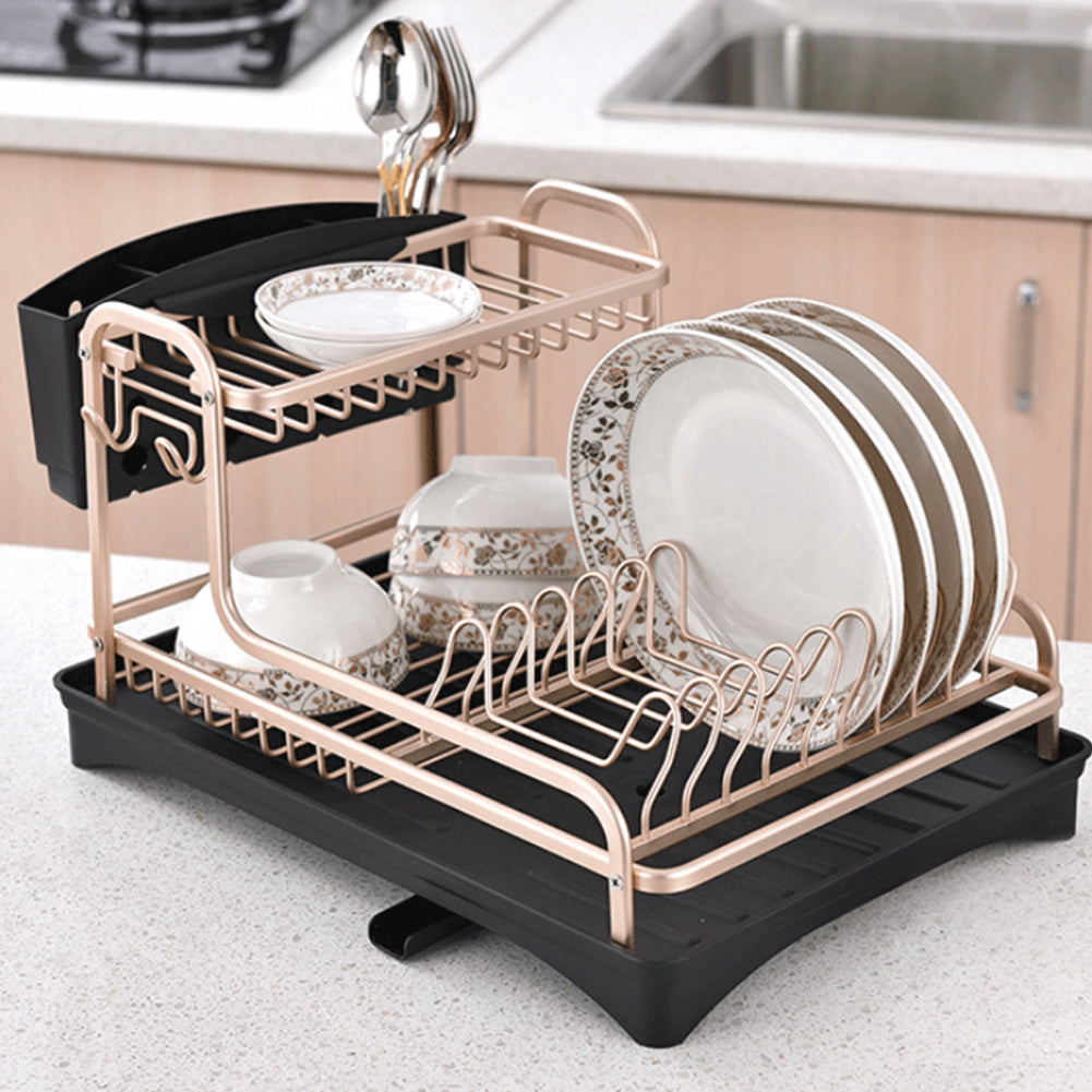 Rose gold dish rack filled with patterned plates, bowls and spoons beside a kitchen sink