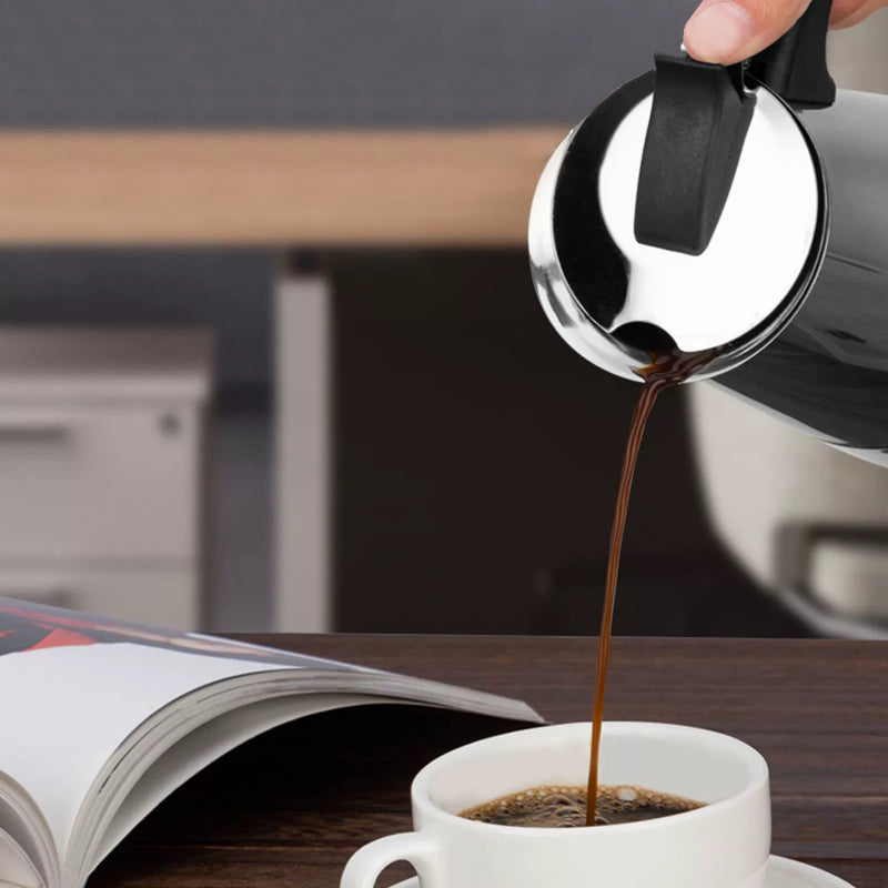 Coffee pouring from the steel moka pot into a white cup