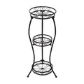 Empty black iron plant stand with three round scrollwork tiers on white