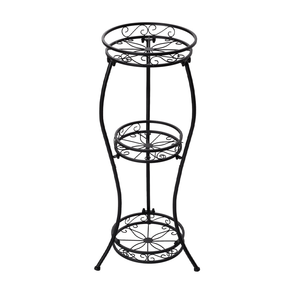 Empty black iron plant stand with three round scrollwork tiers on white