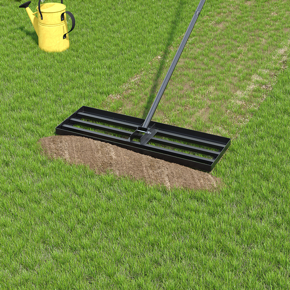 The levelling head resting on a spread of soil in the middle of a lawn, a yellow metal watering can standing on the grass behind it.