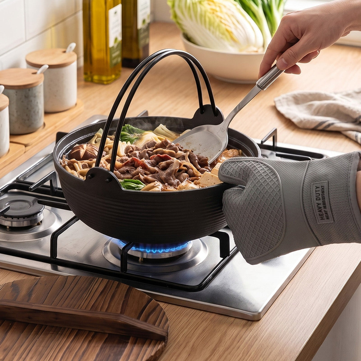 Beef and cabbage simmering in the nabe pot on a gas hob, lifted with a slotted spoon