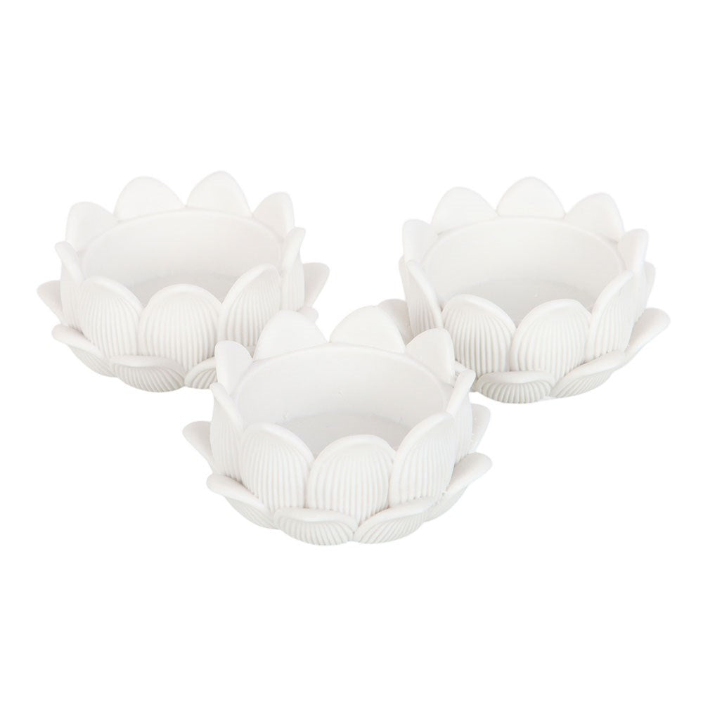 Three white resin lotus flower tealight holders on white