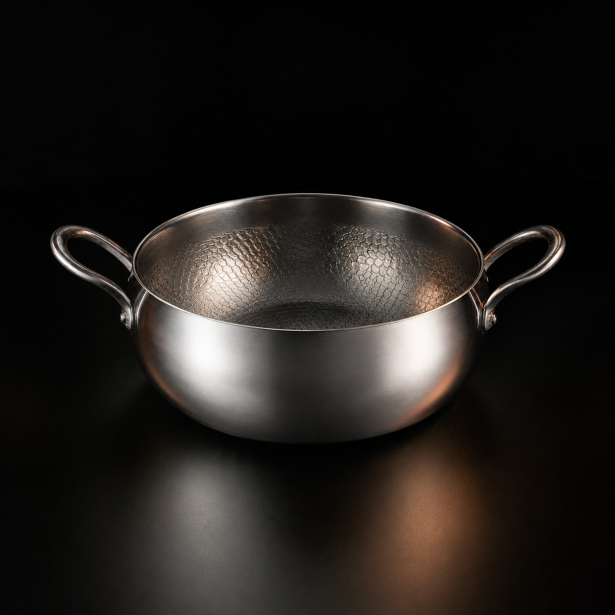 A deep two-handled titanium pot with a hammered inner surface and a smooth polished body, on a black studio background.