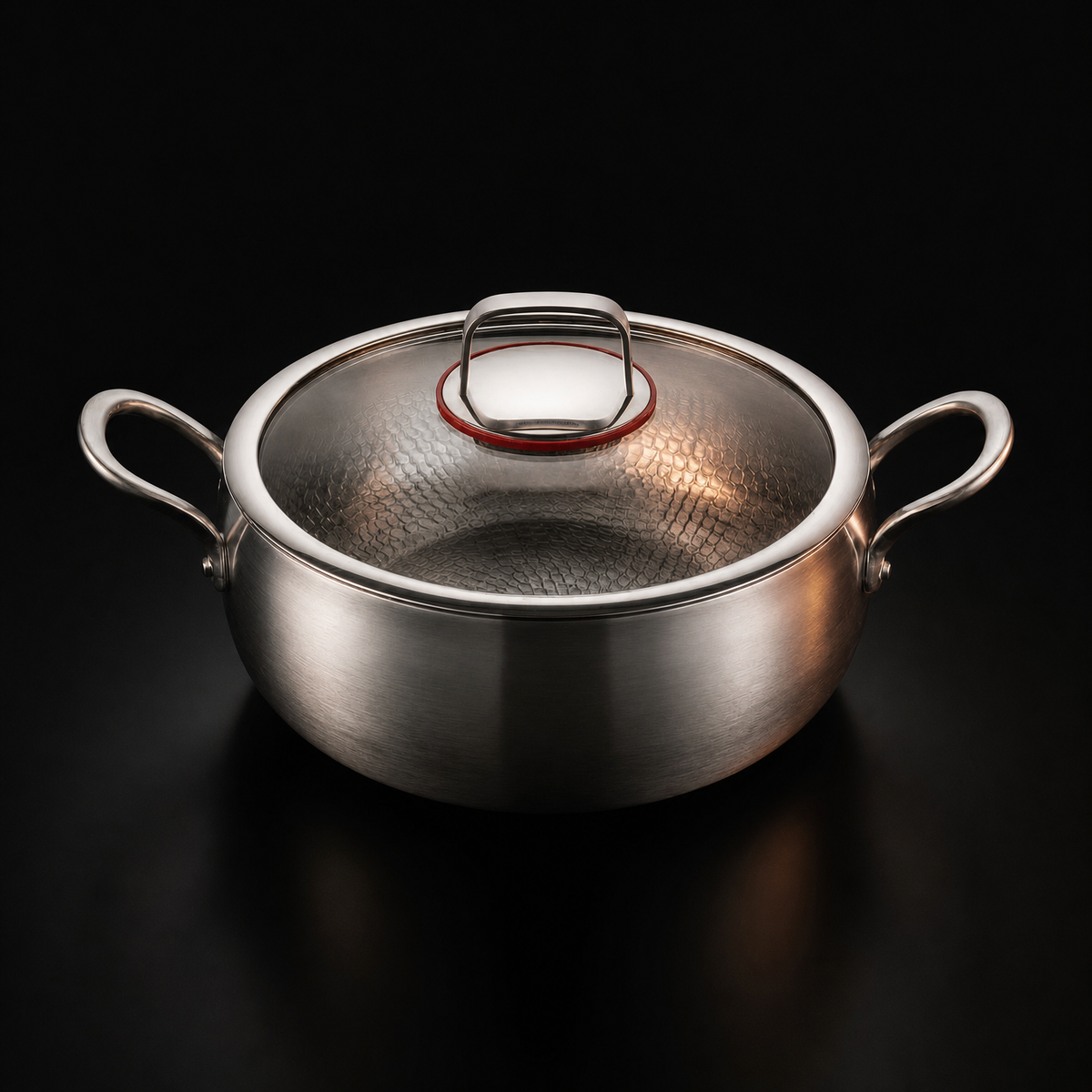 The same pot closed under a clear glass lid with a metal rim and a looped metal handle, on a black studio background.