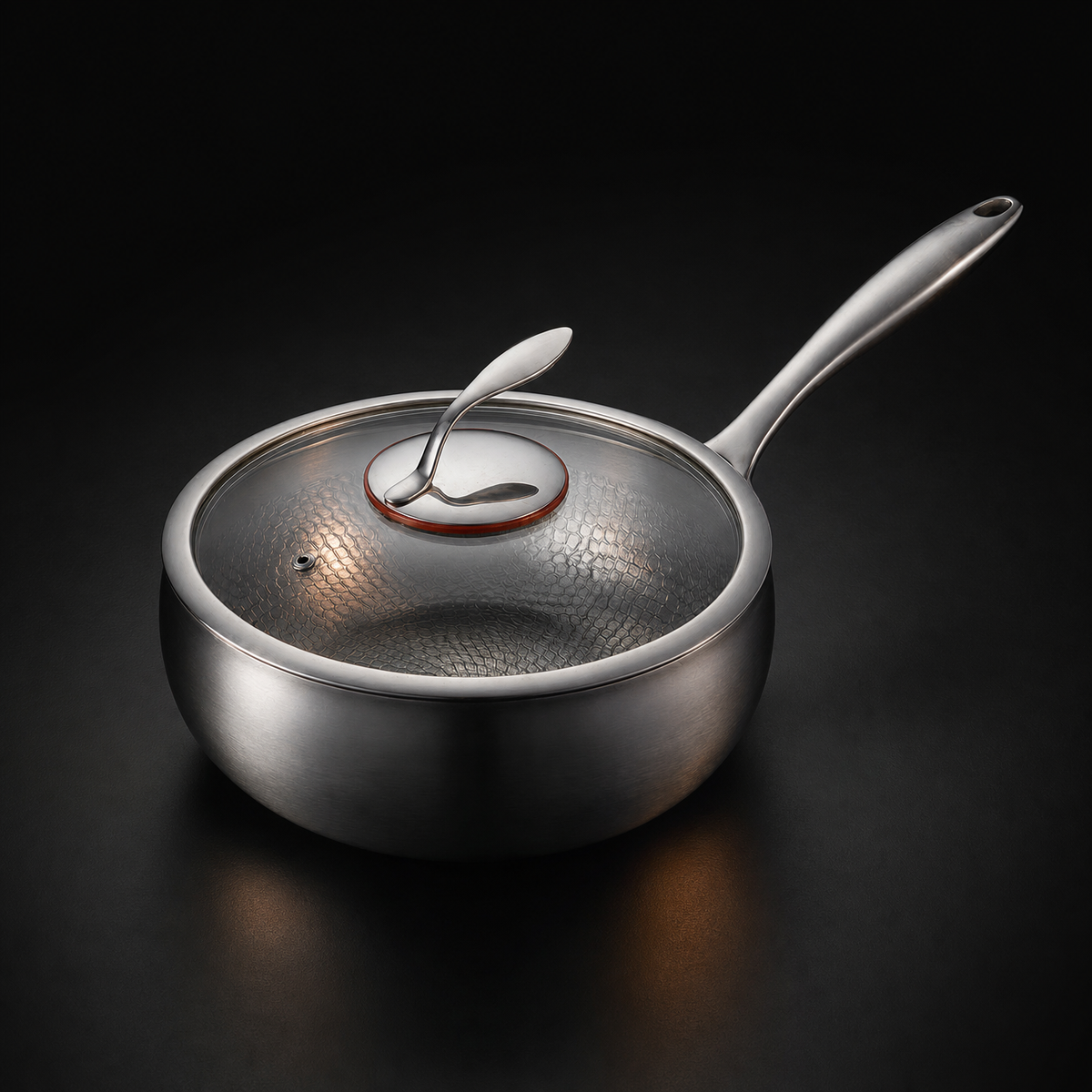 The same pan closed with a clear glass lid, its metal knob and small steam vent visible, against a dark studio background.