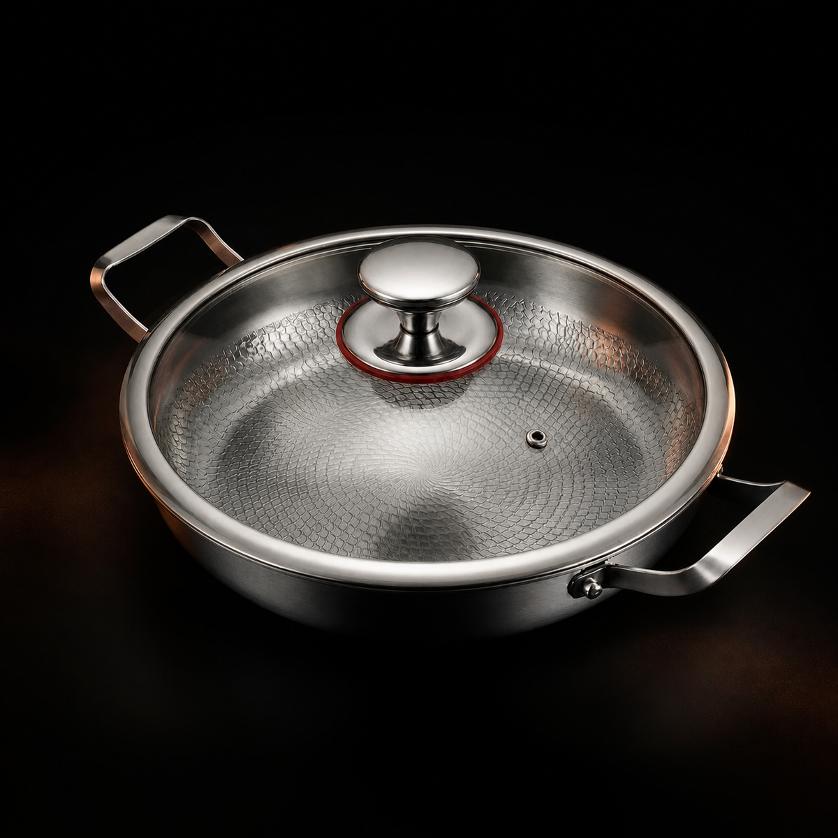 The pan fitted with a clear glass lid, its metal rim, steel knob and small steam vent visible over the hammered base.