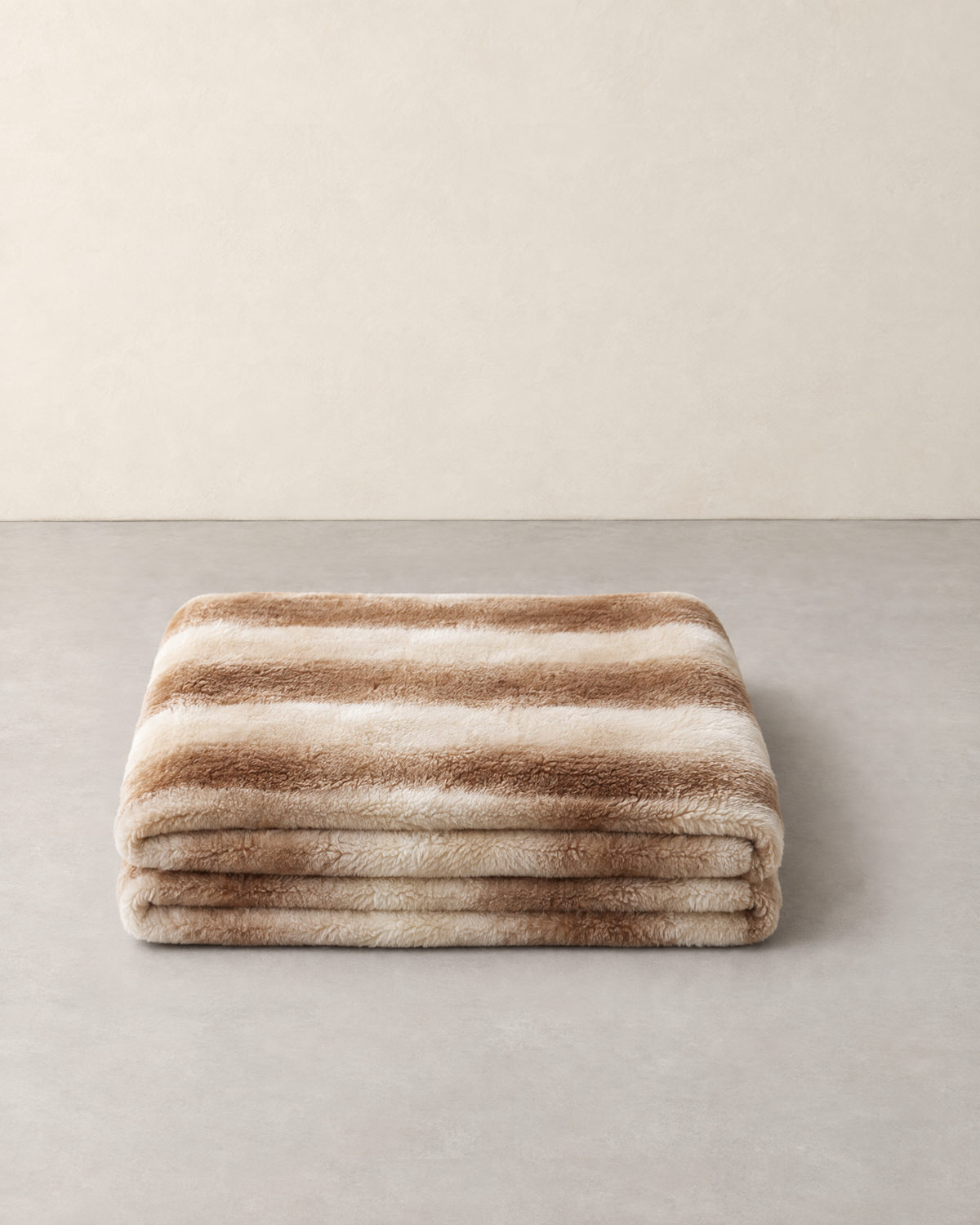 Double-sided plush blanket with light brown and cream gradient stripes, folded