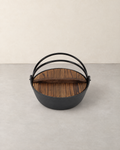 Black cast iron nabe pot with a brown wooden lid and two arched metal handles