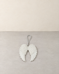 White double angel wing decoration with glitter feathers and a silver ribbon, lying flat