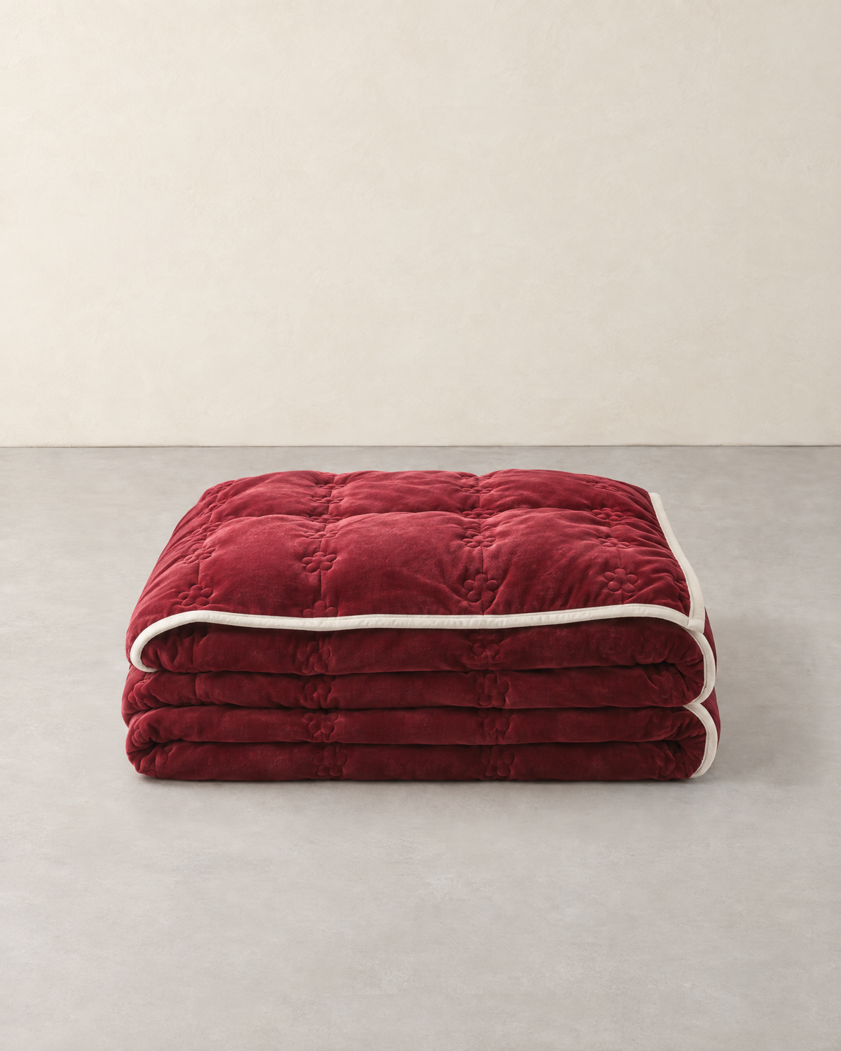 Thick wine red quilted plush blanket with a cream edge, folded