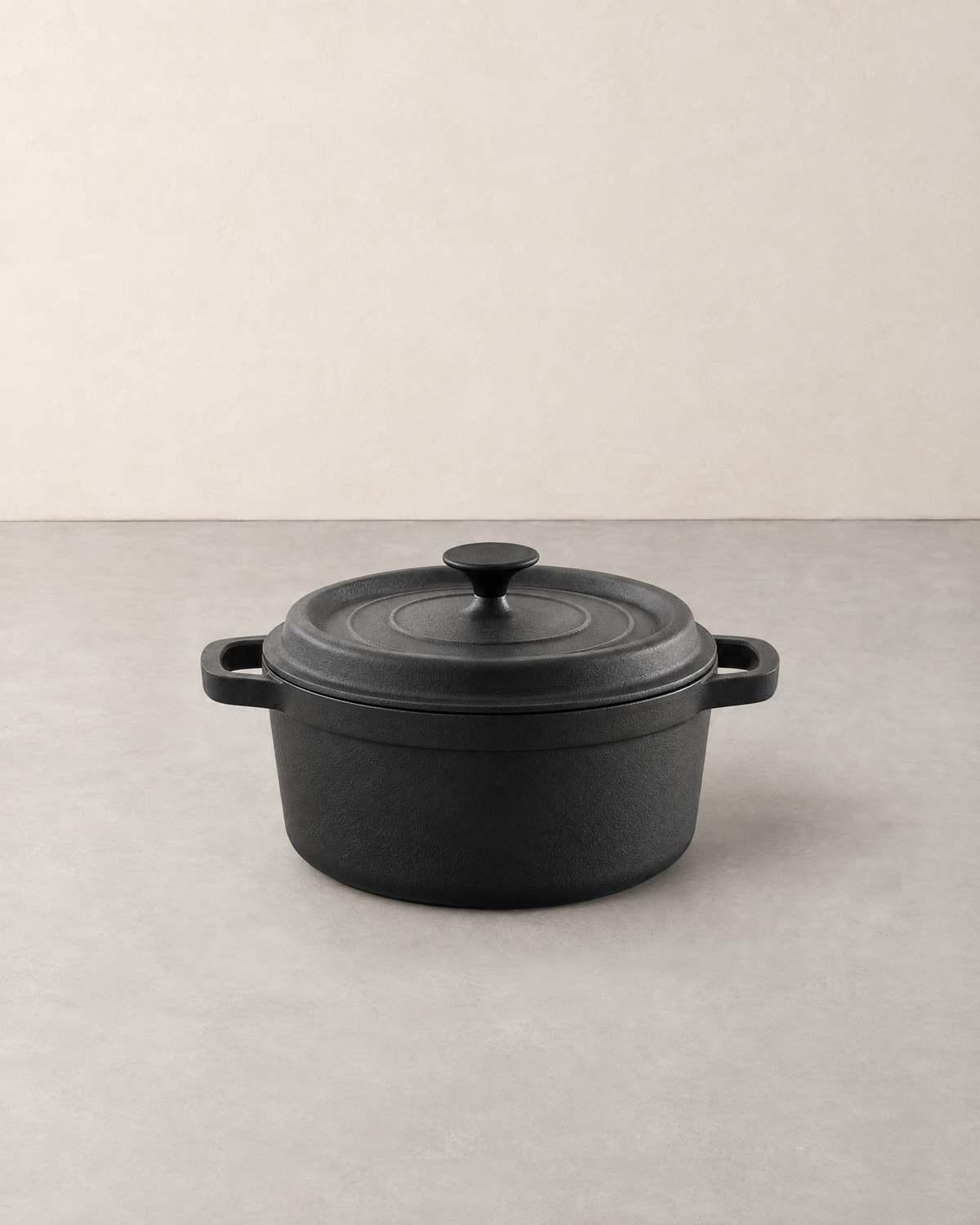 Round black cast iron Dutch oven with lid and two loop handles