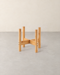 Low bamboo plant pot stand with four round legs and a cross brace, empty