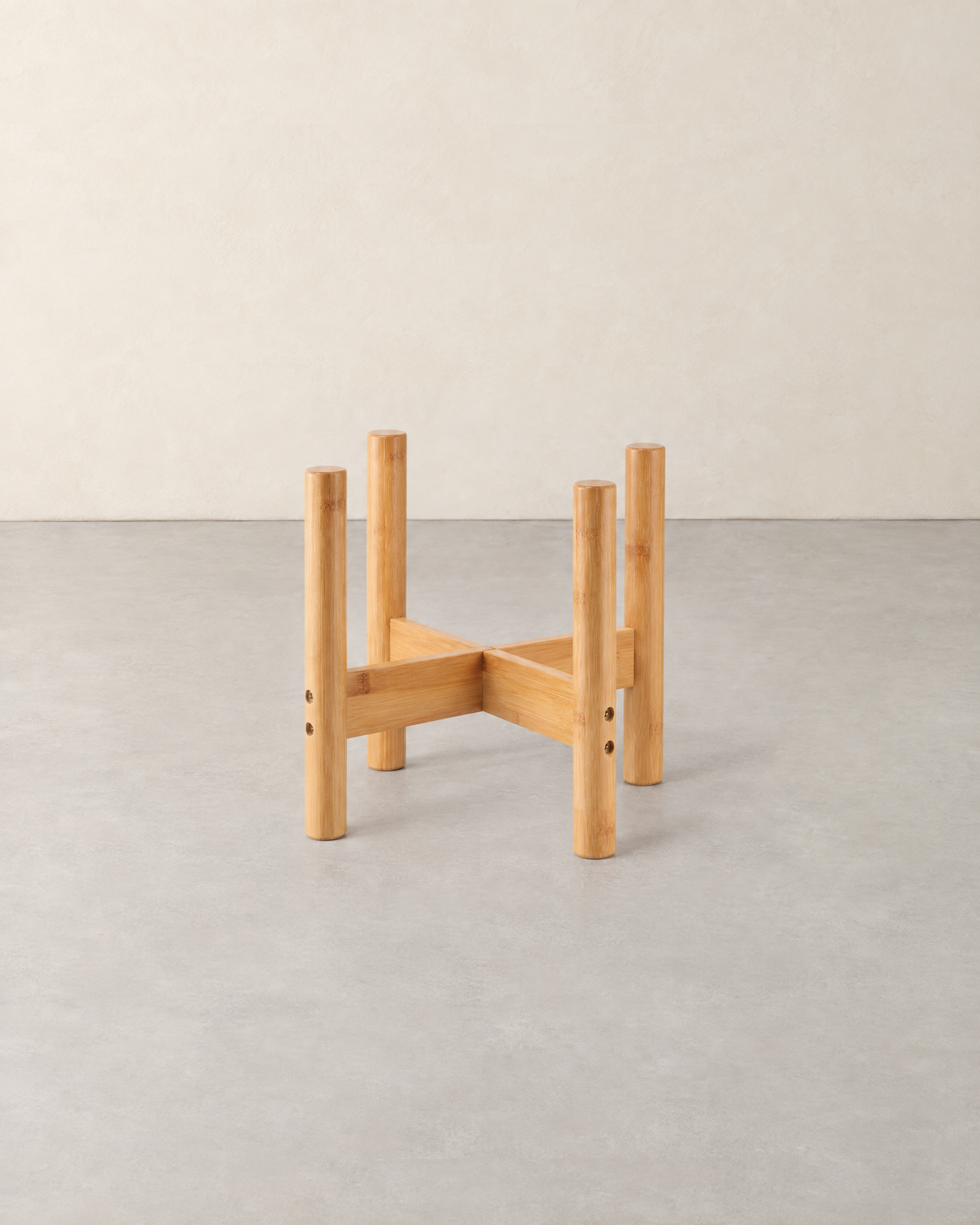 Low bamboo plant pot stand with four round legs and a cross brace, empty