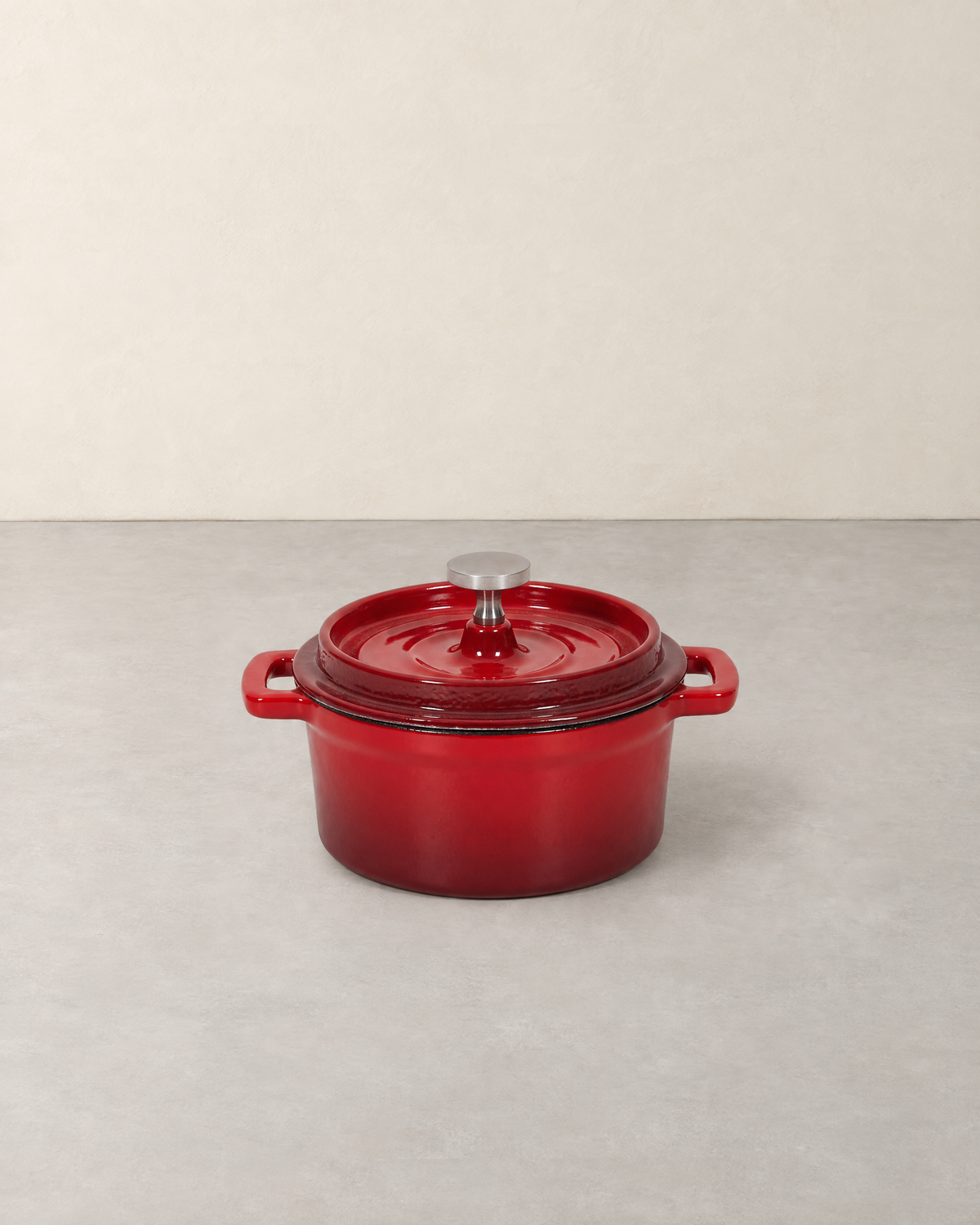 Small red enamelled cast iron Dutch oven with ringed lid, steel knob and two loop handles