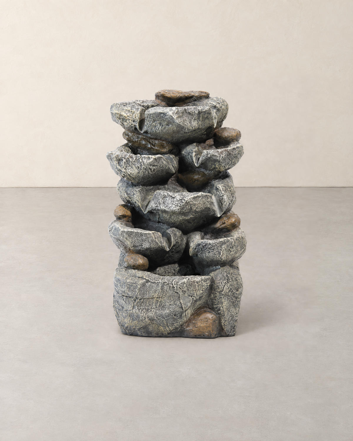 Grey stone-effect rock cascade fountain with brown pebble accents, standing dry